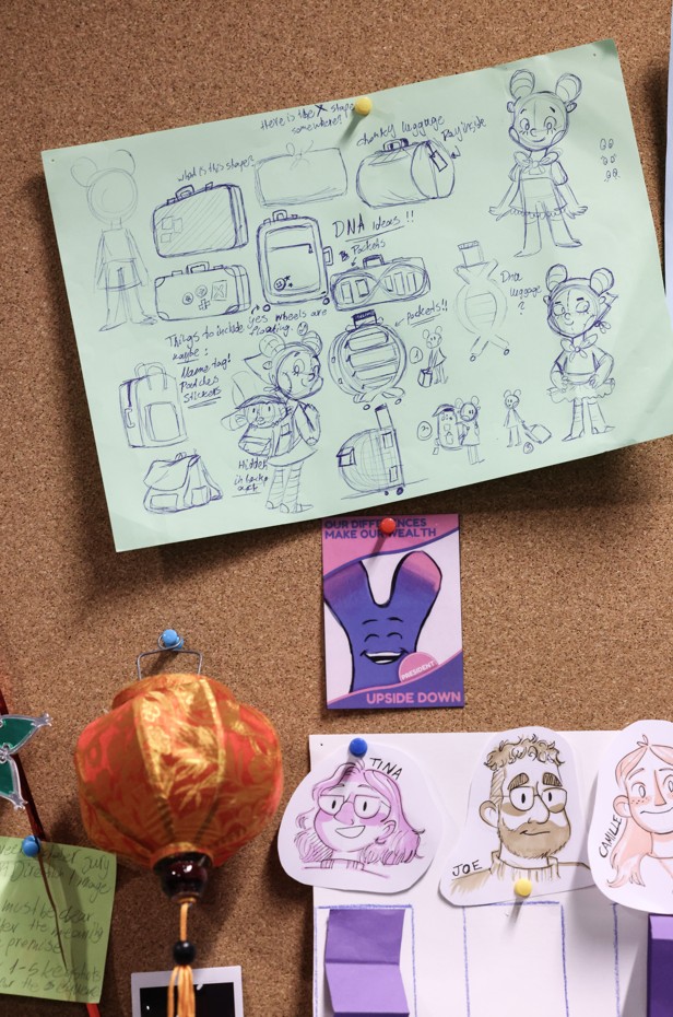 Panneau en liège recouvert de croquis, illustrations de personnages, recherches graphiques et éléments décoratifs, témoignant d’un processus créatif.