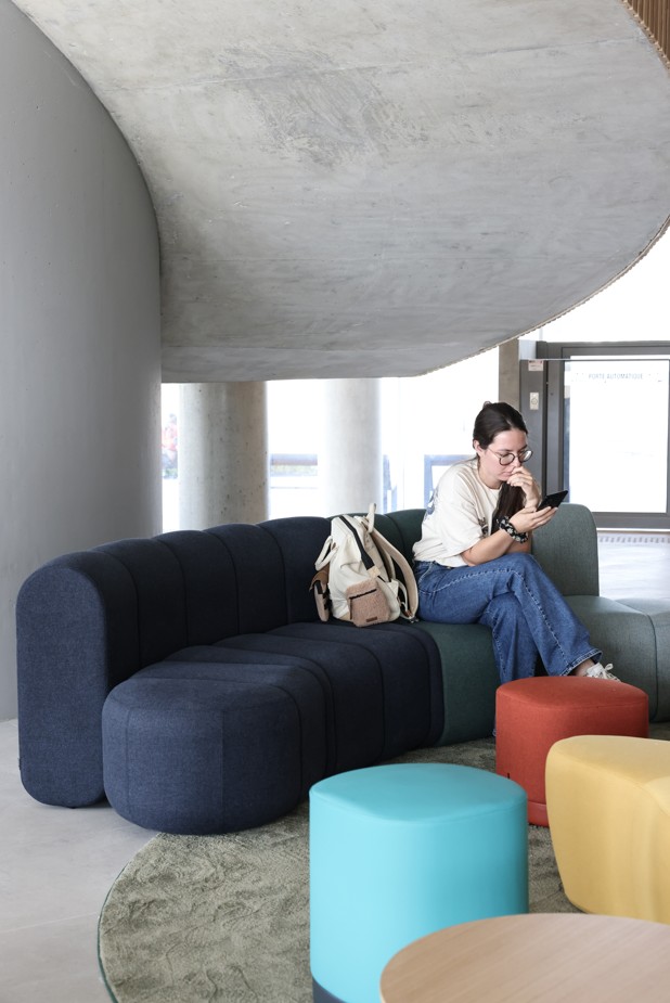 A student sitting in the hall of the ESMA campus, a modern relaxation area.