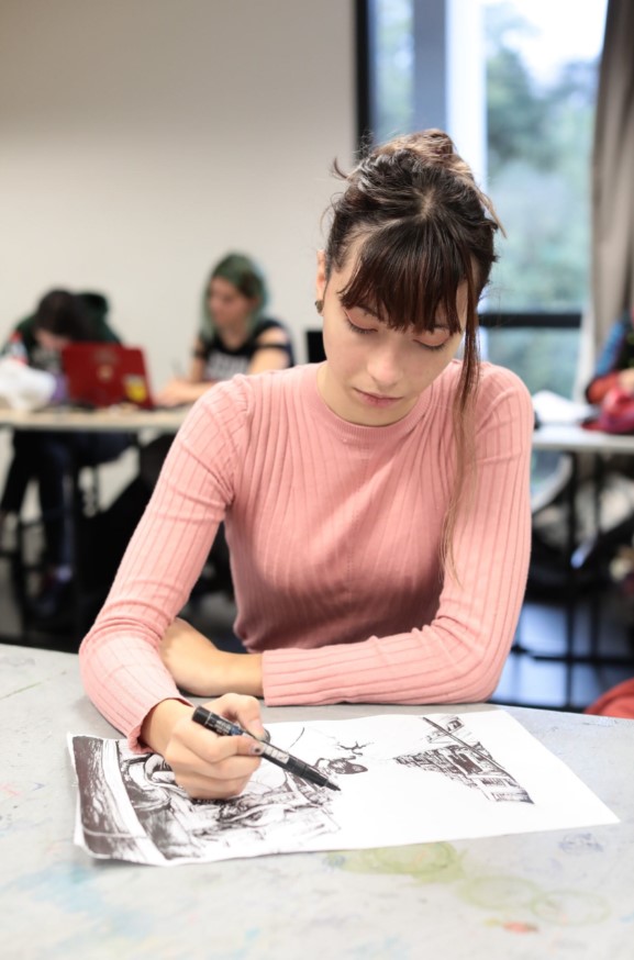Étudiante concentrée en train de dessiner en cours.